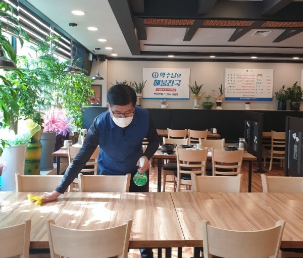 [사진설명]'박주남의 해물천국'의 박주만 대표가 코로나19 감염 예방을 위해 손님들의 탁자에 일일히 손소독을 하고 있다.