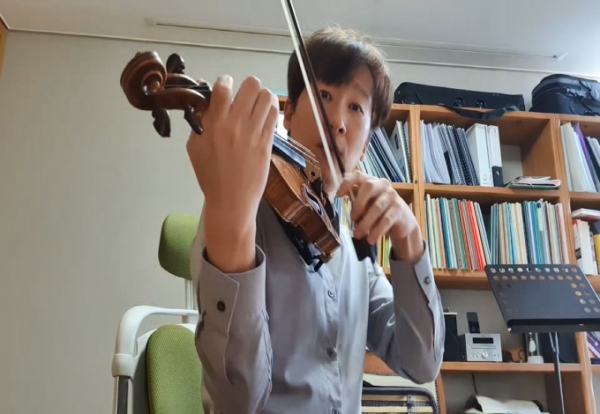 [사진설명]‘놀라운오케스트라’의 권 명 음악감독이 단원에게 동영상으로 연주 기술을 설명하고 있다.